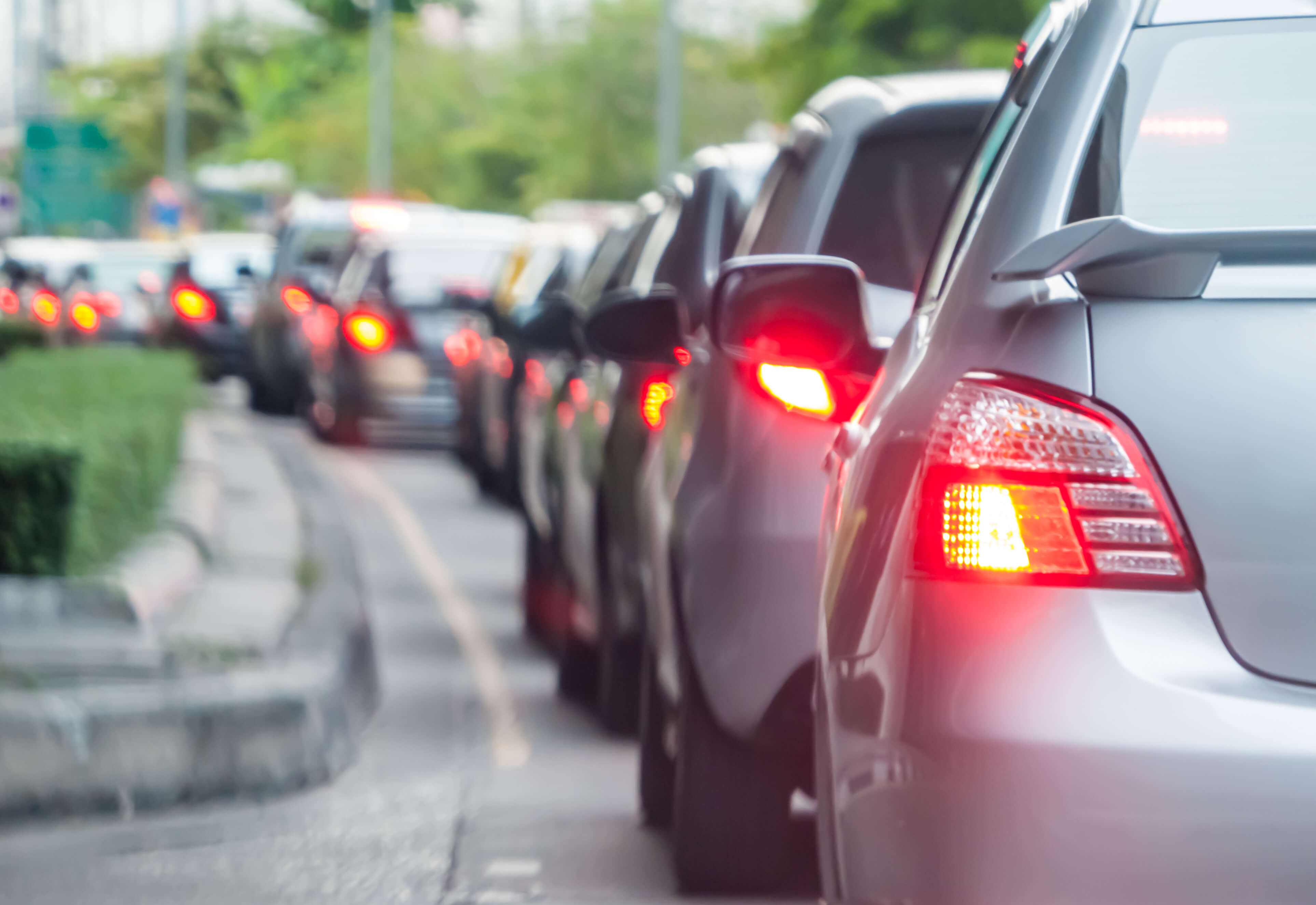 A long line of cars with their brake lights on due to an accident.